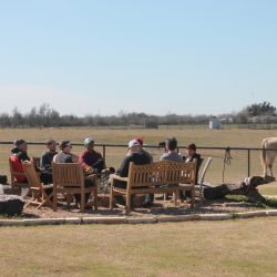 A group of men sitting together outside, set on a ranch in Texas.